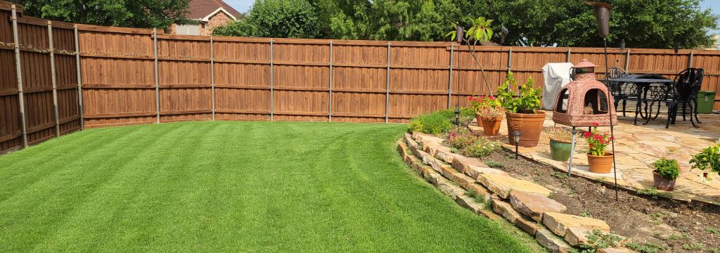 Maintained backyard with mowed lawn and landscape bed in Rowlett, TX.
