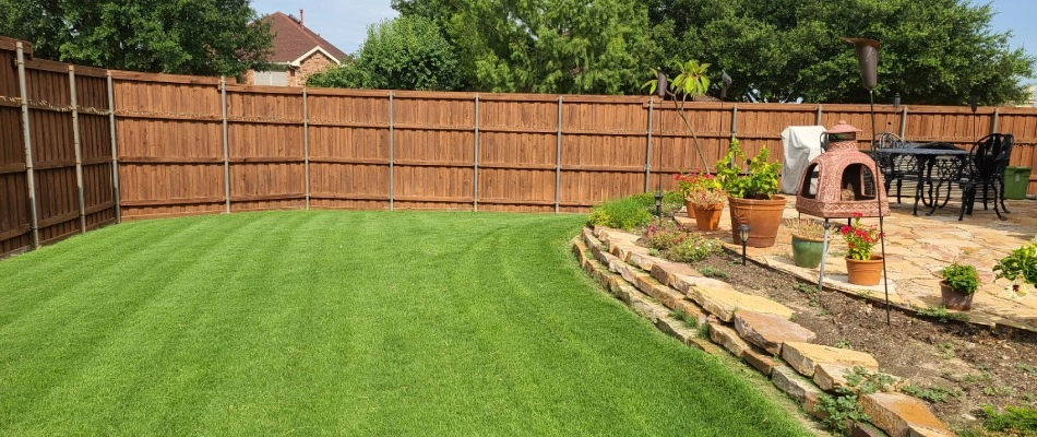 A freshly mowed backyard lawn with retaining wall for a landscape bed in Rockwall, TX.